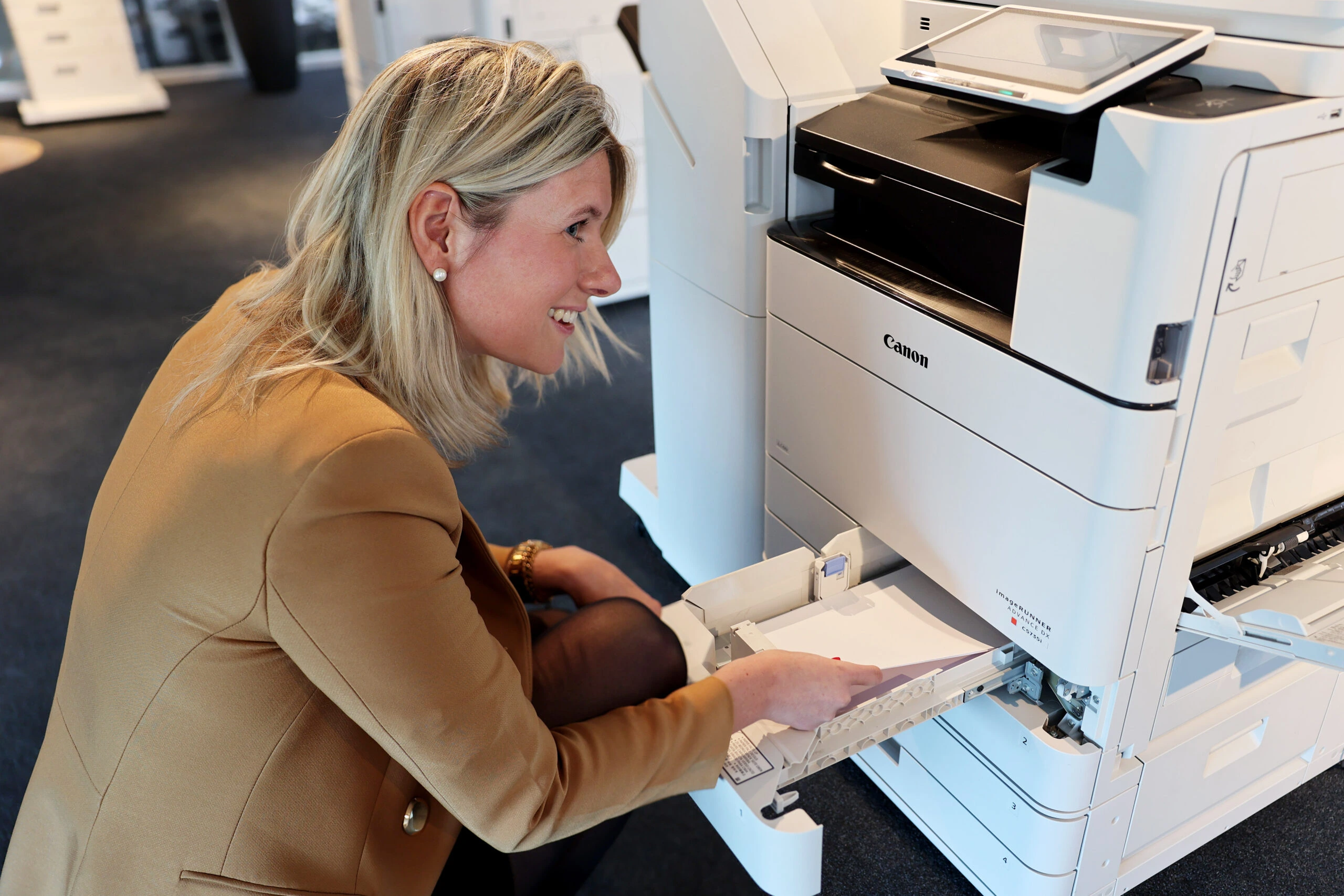Een medewerker in een kantooromgeving vult papier bij in een Canon printer – een praktisch voorbeeld van onze printoplossingen.