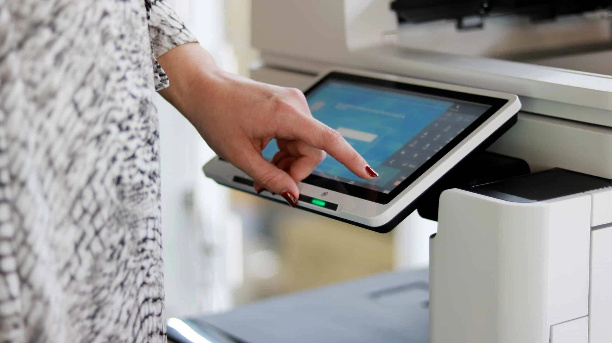 Een hand bedient het touchscreen van een printer – een detail dat de gebruiksvriendelijkheid van onze printoplossingen benadrukt.