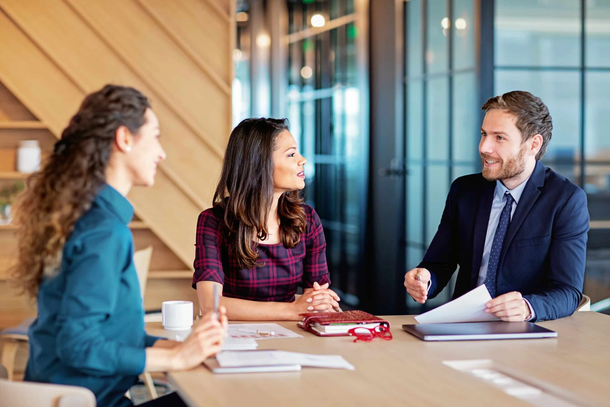 Drie collega’s overleggen aan een vergadertafel met documenten – een moment waarop onze printoplossingen bijdragen aan effectieve samenwerking.